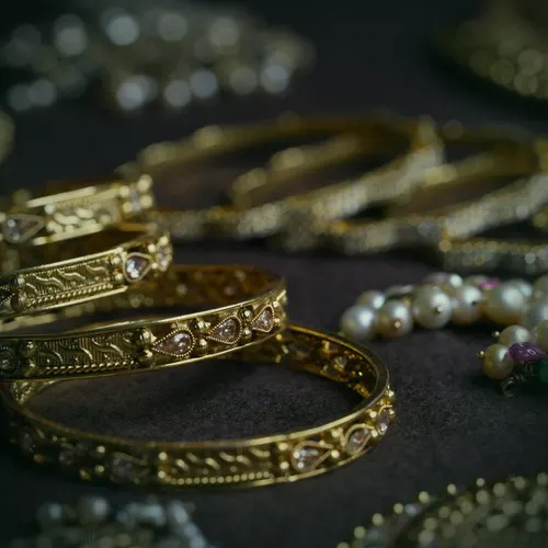 A 22 carat gold antique-finish bangle with raised work and small clear stones.