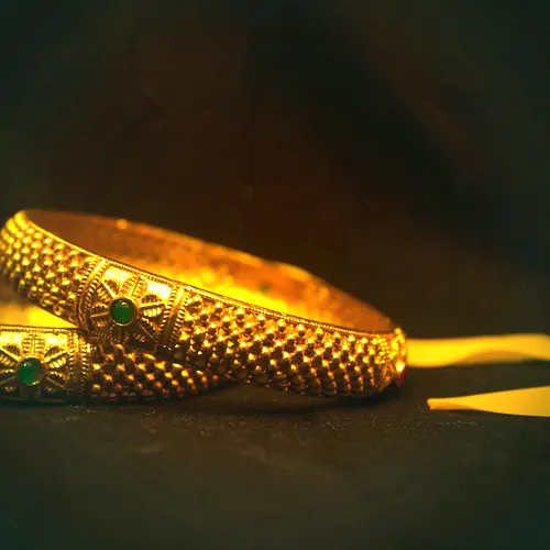 A single 22 carat gold kada bangle with beaded texture and small emerald cabochons.