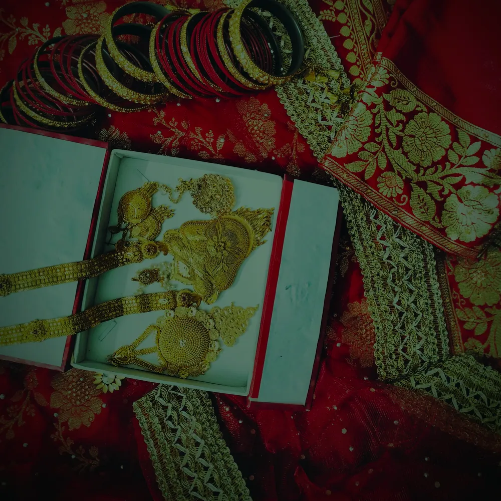 A heavy 22 carat gold bridal set in its presentation box, on a red bridal saree.
