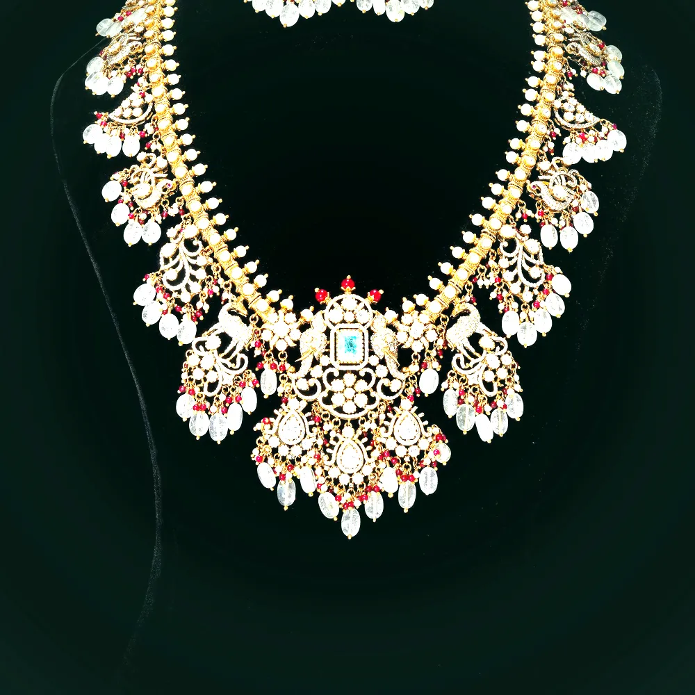 An 18 carat gold polki bridal necklace with uncut diamonds, ruby beads and moonstone drops, with matching earrings, on black velvet.