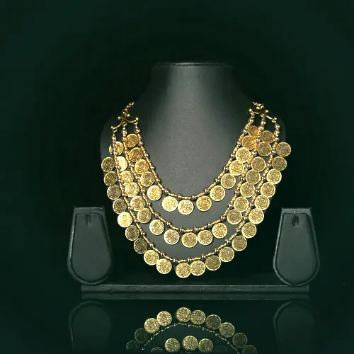 A three-row 22 carat gold kasu malai coin necklace on a display bust.