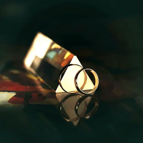 Two plain polished 22 carat gold band rings on a dark reflective surface.